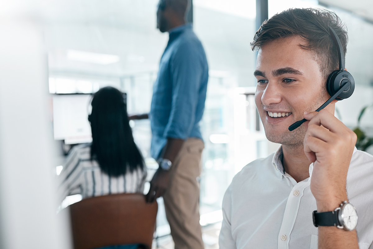 Customer service representative wearing a headset and smiling in a modern call center office