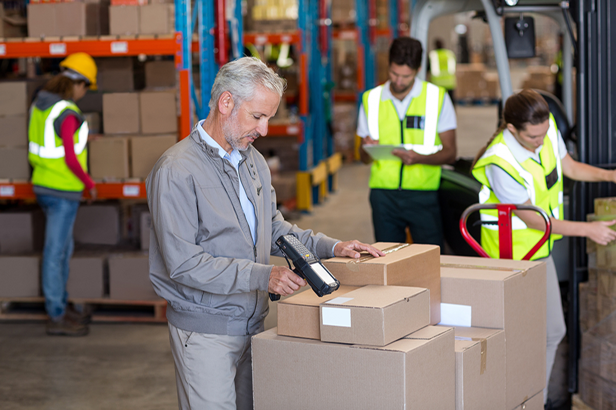Warehouse team scanning barcoded boxes with handheld barcode scanners for inventory management